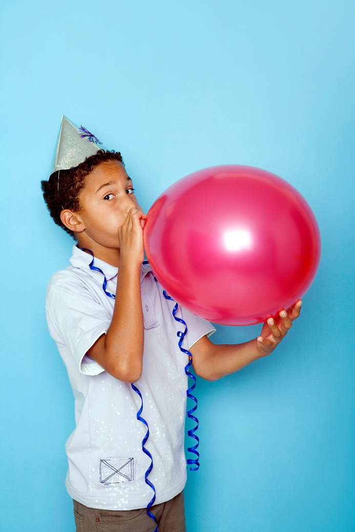 Boy blowing up a balloon